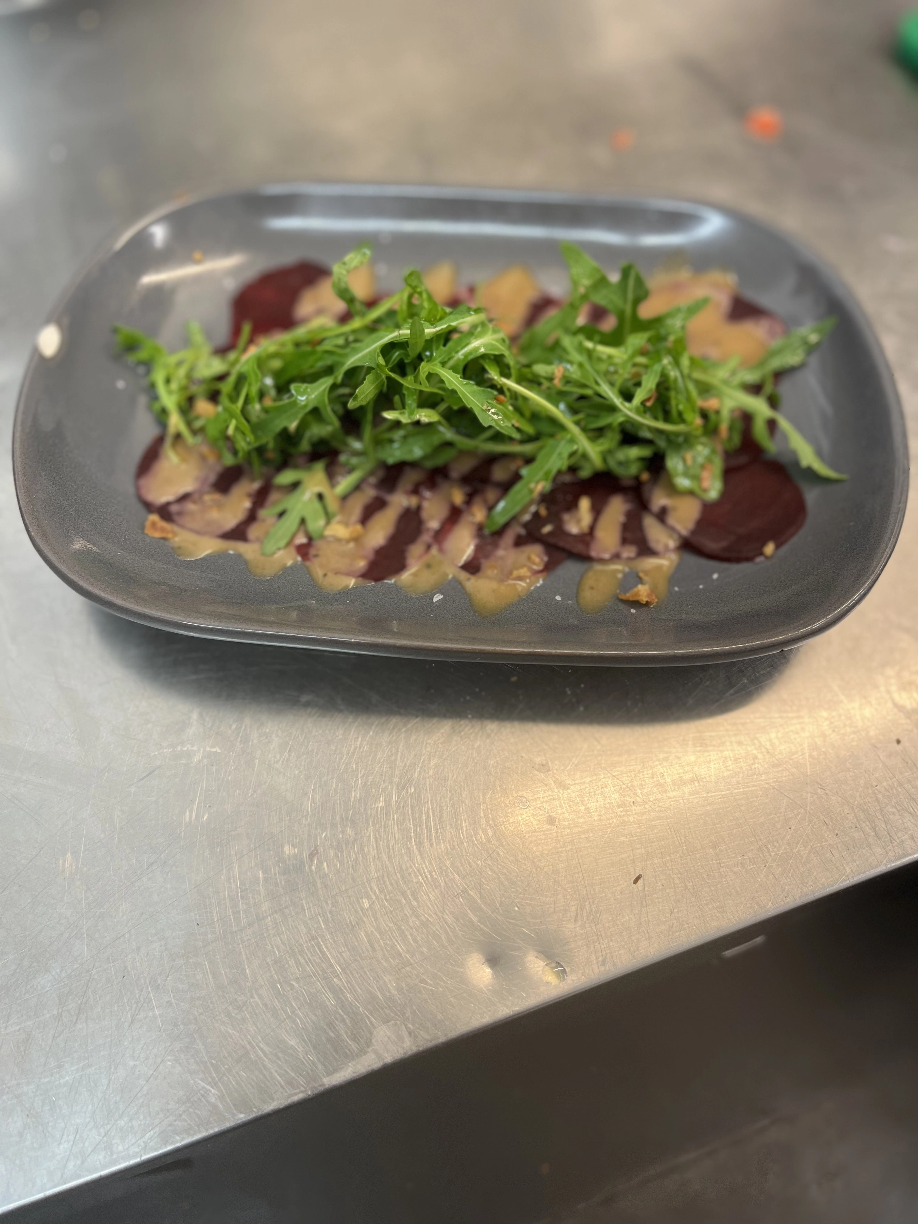 Beetroot Carpaccio, Rocket Leaves And Tahini Dressing Topped With Crispy Onions